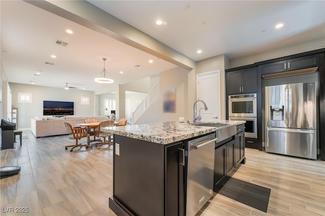 2575 Hazelburn Ave, Henderson, NV 89044 - kitchen with appliances with stainless steel finishes, a sink, open floor plan, light stone counters, and recessed lighting