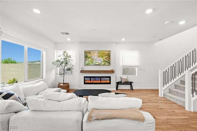 11652 Desert Hollow Ave, Las Vegas, NV 89138 - living room with stairs, light wood-style flooring, recessed lighting, a glass covered fireplace, and baseboards