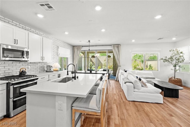 11652 Desert Hollow Ave, Las Vegas, NV 89138 - kitchen with appliances with stainless steel finishes, a sink, light countertops, light wood-style floors, and open floor plan