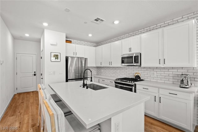 11652 Desert Hollow Ave, Las Vegas, NV 89138 - kitchen with stainless steel appliances, a sink, a kitchen island with sink, backsplash, and white cabinets
