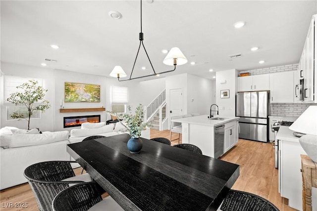 11652 Desert Hollow Ave, Las Vegas, NV 89138 - dining area with light wood-style floors, stairs, a glass covered fireplace, and recessed lighting
