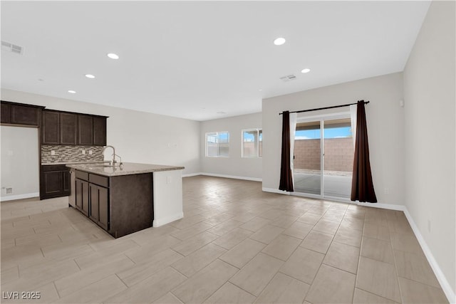 367 Wilford Springs St, Henderson, NV 89014 - kitchen with dark brown cabinets, baseboards, open floor plan, decorative backsplash, and recessed lighting