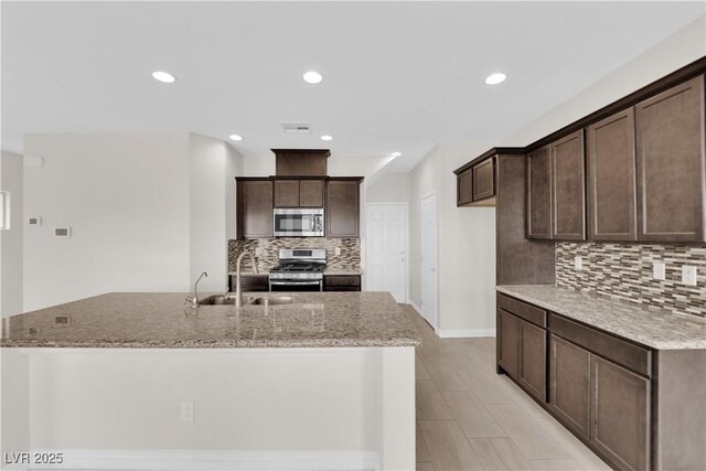367 Wilford Springs St, Henderson, NV 89014 - kitchen featuring a sink, appliances with stainless steel finishes, dark brown cabinets, an island with sink, and backsplash