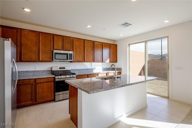 89 Via Franello, Henderson, NV 89011 - kitchen featuring stainless steel appliances, a sink, light tile patterned flooring, light stone counters, and brown cabinets