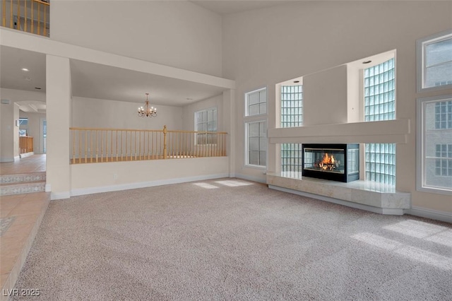1312 Fragrant Spruce Ave, Las Vegas, NV 89123 - unfurnished living room featuring carpet floors, a towering ceiling, a multi sided fireplace, a chandelier, and plenty of natural light