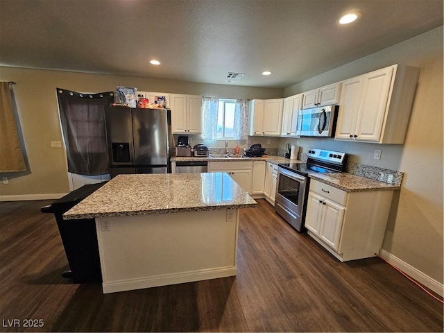 1870 Upland Ave, Pahrump, NV 89048 - kitchen featuring appliances with stainless steel finishes, baseboards, dark wood finished floors, a center island, and light stone countertops