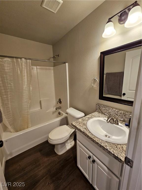 1870 Upland Ave, Pahrump, NV 89048 - bathroom featuring wood finished floors, shower / tub combo with curtain, vanity, toilet, and a textured wall