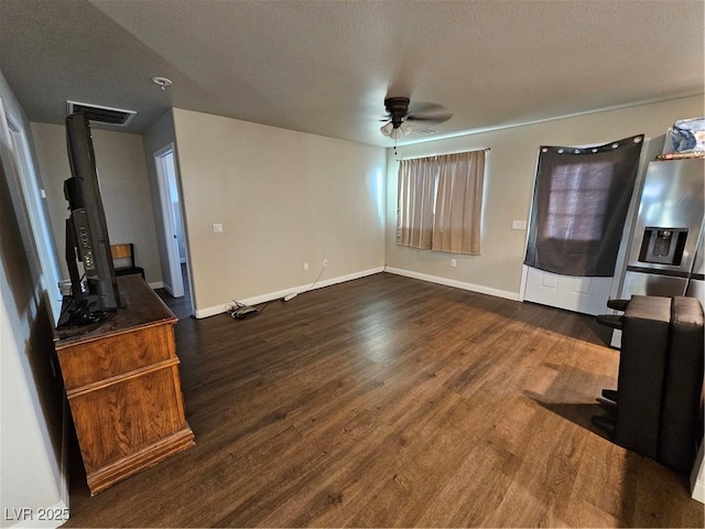 1870 Upland Ave, Pahrump, NV 89048 - unfurnished living room featuring a ceiling fan, dark wood finished floors, baseboards, a textured ceiling, and a wood stove