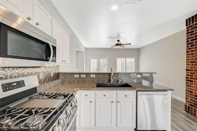 5931 Allanche Ave, Las Vegas, NV 89141 - kitchen with stainless steel appliances, a ceiling fan, a peninsula, light wood-type flooring, and white cabinets