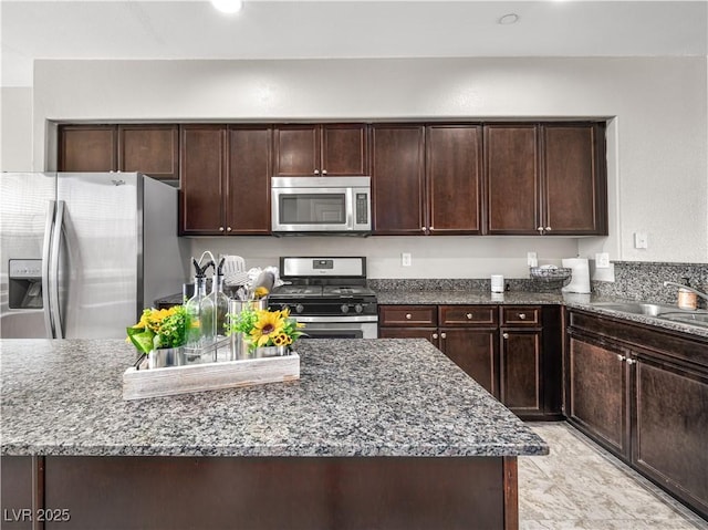 4563 Townwall St, Las Vegas, NV 89115 - kitchen featuring stainless steel appliances, dark stone counters, a sink, and dark brown cabinetry