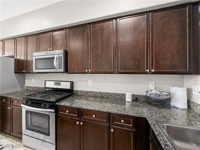 4563 Townwall St, Las Vegas, NV 89115 - kitchen featuring appliances with stainless steel finishes, dark brown cabinetry, and dark stone countertops