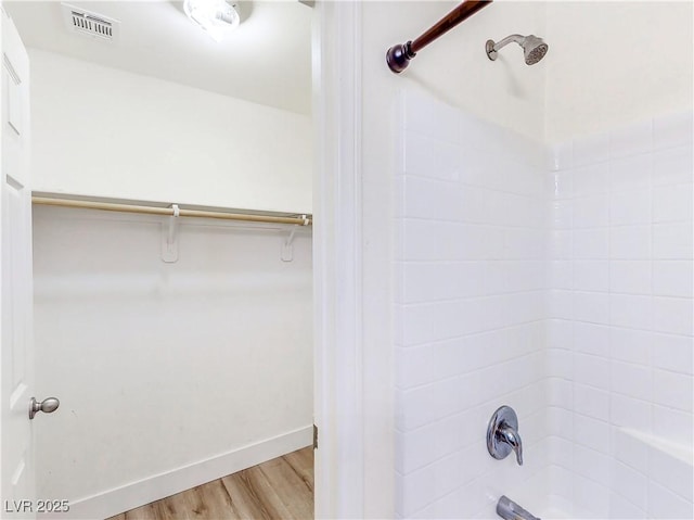 4563 Townwall St, Las Vegas, NV 89115 - bathroom with  shower combination, wood finished floors, a walk in closet, and baseboards