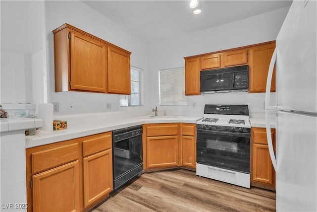 1300 S Arlington St Unit 120, Las Vegas, NV 89104 - kitchen with black appliances, light wood finished floors, a sink, brown cabinets, and tile countertops