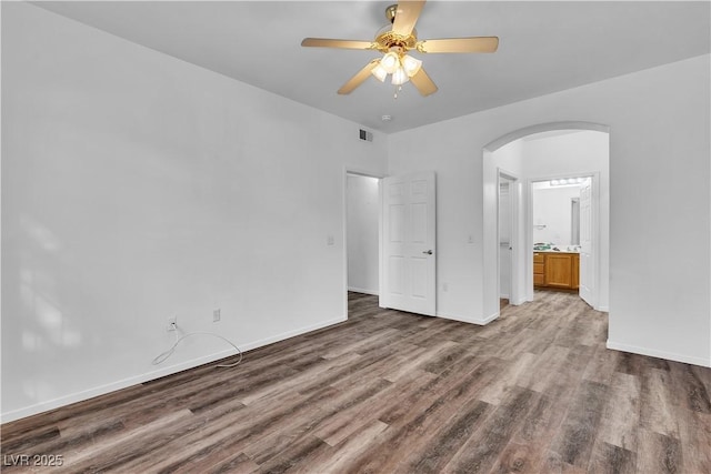 1300 S Arlington St Unit 120, Las Vegas, NV 89104 - unfurnished bedroom featuring arched walkways, wood finished floors, baseboards, connected bathroom, and ceiling fan