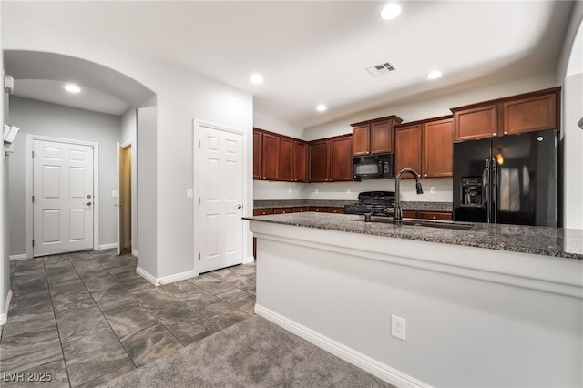 10917 Mount Pendleton St, Las Vegas, NV 89179 - kitchen with black appliances, a sink, dark stone counters, arched walkways, and baseboards