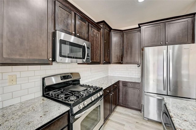 7372 S Palo Real Ct, Las Vegas, NV 89179 - kitchen featuring appliances with stainless steel finishes, light stone countertops, dark brown cabinets, and backsplash