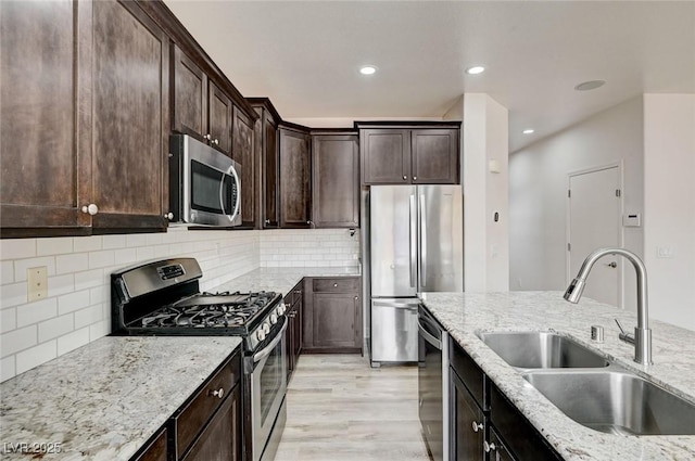 7372 S Palo Real Ct, Las Vegas, NV 89179 - kitchen with stainless steel appliances, light stone counters, light wood-type flooring, dark brown cabinets, and tasteful backsplash