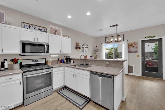 6108 Shallow Springs St, Las Vegas, NV 89130 - kitchen with appliances with stainless steel finishes, a sink, a peninsula, white cabinets, and light wood-type flooring