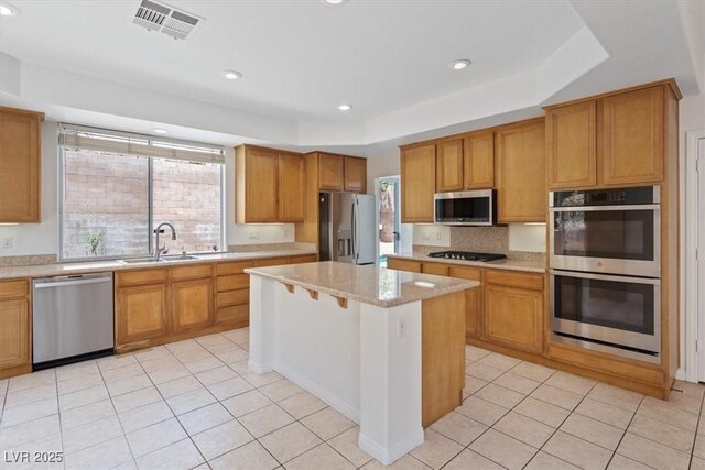 10680 Sapphire Vista Ave, Las Vegas, NV 89144 - kitchen with stainless steel appliances, a sink, a center island, light tile patterned floors, and a raised ceiling