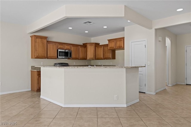 1407 Wheelwright Ct, Mesquite, NV 89034 - kitchen featuring stainless steel microwave, recessed lighting, brown cabinetry, stove, and light tile patterned floors