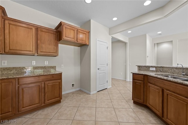 1407 Wheelwright Ct, Mesquite, NV 89034 - kitchen with brown cabinets, a sink, light stone countertops, baseboards, and light tile patterned floors