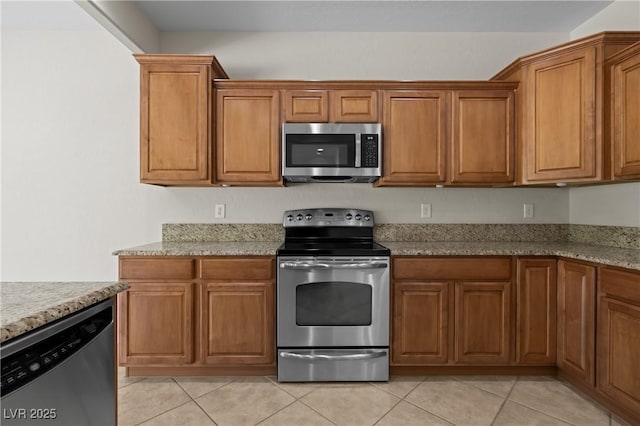 1407 Wheelwright Ct, Mesquite, NV 89034 - kitchen featuring stainless steel appliances, brown cabinets, light tile patterned flooring, and light stone counters