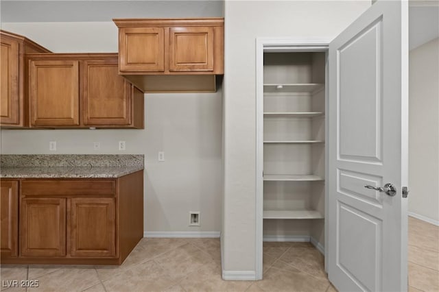 1407 Wheelwright Ct, Mesquite, NV 89034 - kitchen featuring brown cabinets, light stone countertops, baseboards, and light tile patterned floors