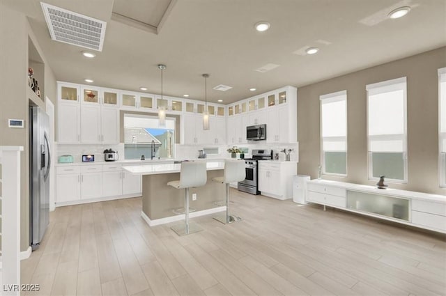 8060 Haywood Estate Ave, Las Vegas, NV 89113 - kitchen with appliances with stainless steel finishes, tasteful backsplash, a center island, glass insert cabinets, and light countertops