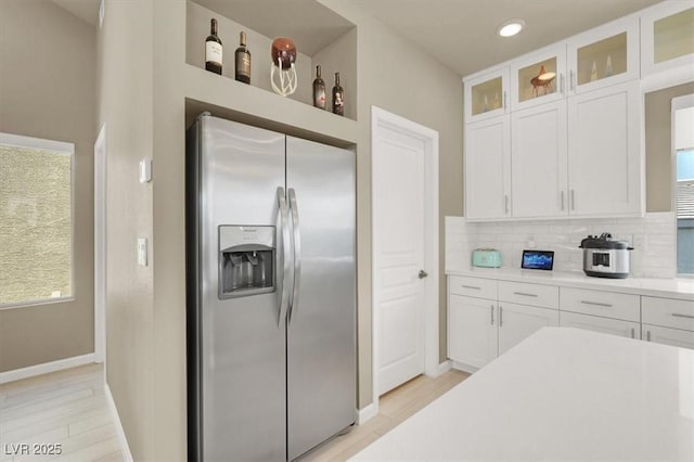 8060 Haywood Estate Ave, Las Vegas, NV 89113 - kitchen with stainless steel refrigerator with ice dispenser, white cabinetry, tasteful backsplash, light countertops, and baseboards