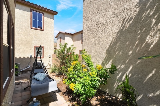 632 Monument Point St, Henderson, NV 89002 - view of side of home with stucco siding, a patio area, a tiled roof, and central AC