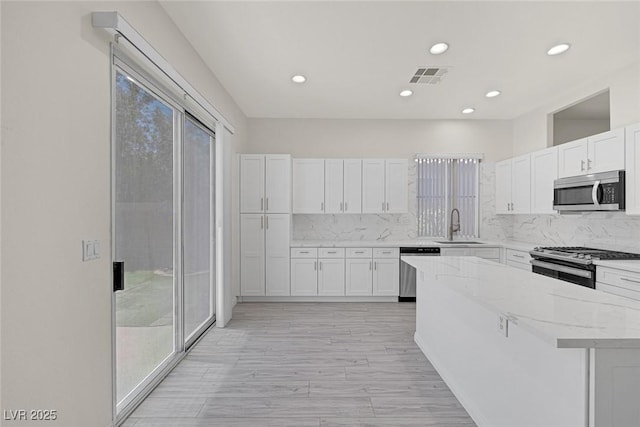 2367 Tilden Way, Henderson, NV 89074 - kitchen with appliances with stainless steel finishes, a kitchen island, white cabinets, decorative backsplash, and recessed lighting