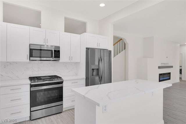 2367 Tilden Way, Henderson, NV 89074 - kitchen featuring appliances with stainless steel finishes, decorative backsplash, white cabinetry, light stone counters, and a center island