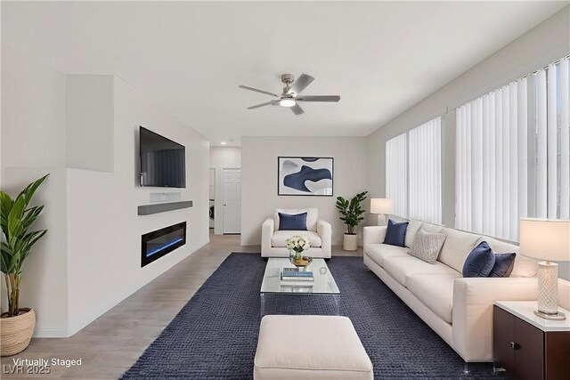 2367 Tilden Way, Henderson, NV 89074 - living room featuring light wood-style floors, a ceiling fan, a glass covered fireplace, and baseboards