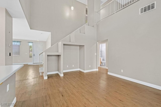 927 Clear Diamond Ave, Las Vegas, NV 89123 - unfurnished living room featuring light wood-style flooring, a towering ceiling, baseboards, and stairway