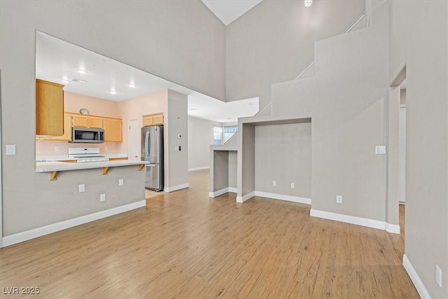 927 Clear Diamond Ave, Las Vegas, NV 89123 - unfurnished living room featuring light wood-style floors, baseboards, and a towering ceiling