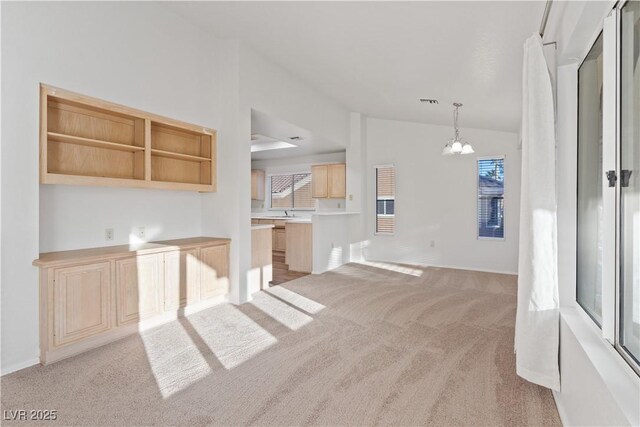9105 Marble Dr, Las Vegas, NV 89134 - kitchen with light colored carpet, vaulted ceiling, a chandelier, pendant lighting, and light brown cabinetry