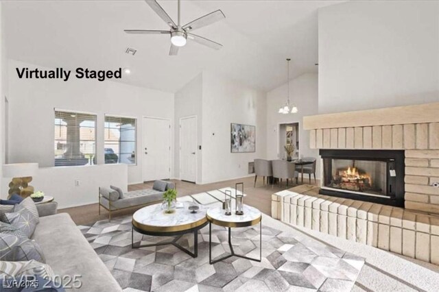 9105 Marble Dr, Las Vegas, NV 89134 - living room featuring high vaulted ceiling, a brick fireplace, a ceiling fan, and a chandelier