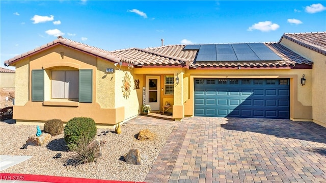 2225 Chandler Ranch Pl, Laughlin, NV 89029 - view of front facade featuring stucco siding, a garage, solar panels, and decorative driveway