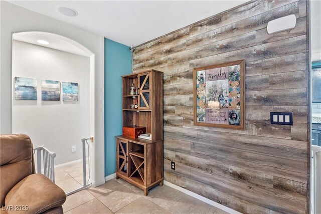 2225 Chandler Ranch Pl, Laughlin, NV 89029 - sitting room featuring wood walls, an accent wall, baseboards, tile patterned flooring, and arched walkways