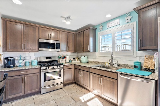 2225 Chandler Ranch Pl, Laughlin, NV 89029 - kitchen featuring stainless steel appliances, a sink, decorative backsplash, light tile patterned floors, and light stone countertops