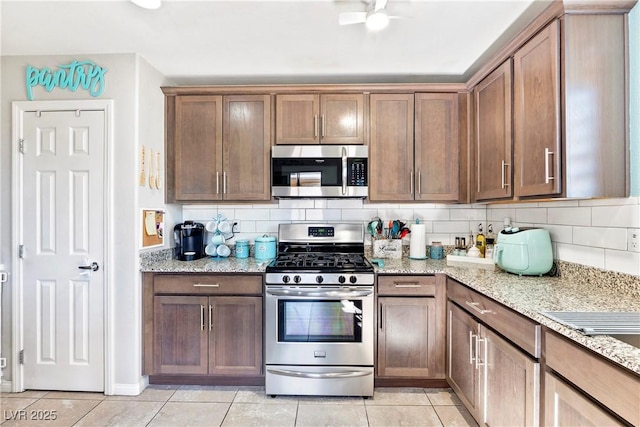2225 Chandler Ranch Pl, Laughlin, NV 89029 - kitchen featuring appliances with stainless steel finishes, light tile patterned flooring, tasteful backsplash, and light stone countertops