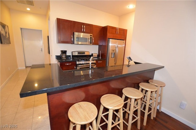 4585 Dean Martin Dr Unit 205, Las Vegas, NV 89103 - kitchen featuring stainless steel appliances, baseboards, a breakfast bar area, recessed lighting, and light tile patterned flooring