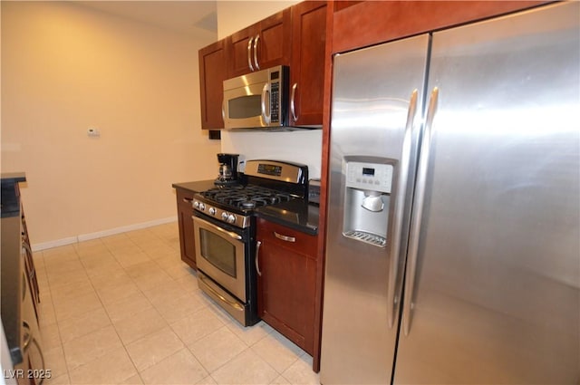 4585 Dean Martin Dr Unit 205, Las Vegas, NV 89103 - kitchen with stainless steel appliances, dark countertops, baseboards, and light tile patterned flooring