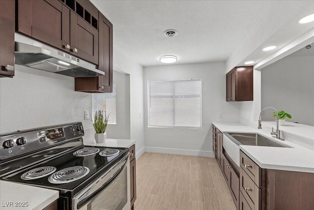2408 Berkley Ave, Las Vegas, NV 89101 - kitchen featuring electric range, under cabinet range hood, a sink, light countertops, and dark brown cabinetry
