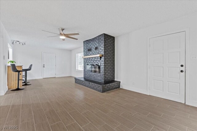 2408 Berkley Ave, Las Vegas, NV 89101 - unfurnished living room with ceiling fan, wood finished floors, a textured ceiling, baseboards, and a fireplace
