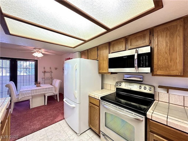 4151 Sanderling Cir Unit 351, Las Vegas, NV 89103 - kitchen featuring appliances with stainless steel finishes, tile counters, light carpet, and brown cabinets
