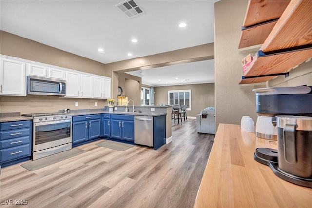 7029 Bocaire Dr, Las Vegas, NV 89131 - kitchen with stainless steel appliances, blue cabinetry, a sink, white cabinets, and a peninsula