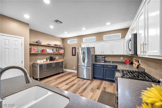 7029 Bocaire Dr, Las Vegas, NV 89131 - kitchen featuring stainless steel appliances, a sink, white cabinetry, blue cabinets, and light wood finished floors
