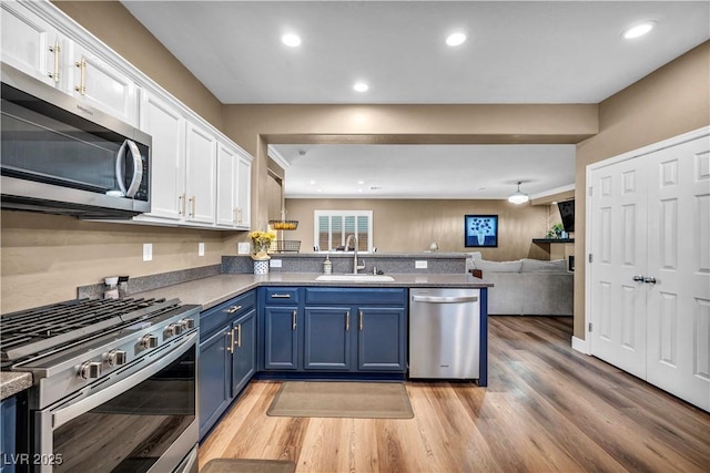 7029 Bocaire Dr, Las Vegas, NV 89131 - kitchen featuring appliances with stainless steel finishes, a sink, blue cabinets, white cabinets, and a peninsula