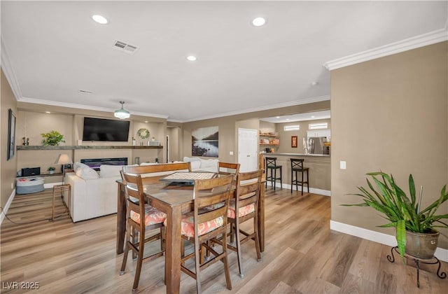 7029 Bocaire Dr, Las Vegas, NV 89131 - dining area featuring a glass covered fireplace, light wood finished floors, baseboards, ornamental molding, and recessed lighting
